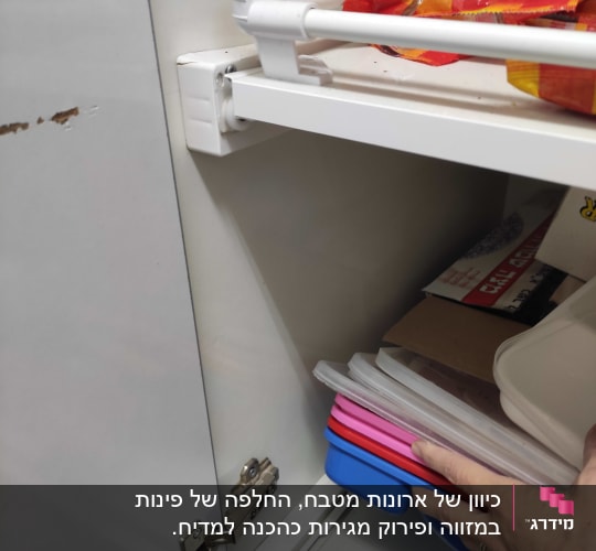 יד מחזיקה קופסאות פלסטיק צבעוניות בארון מטבח